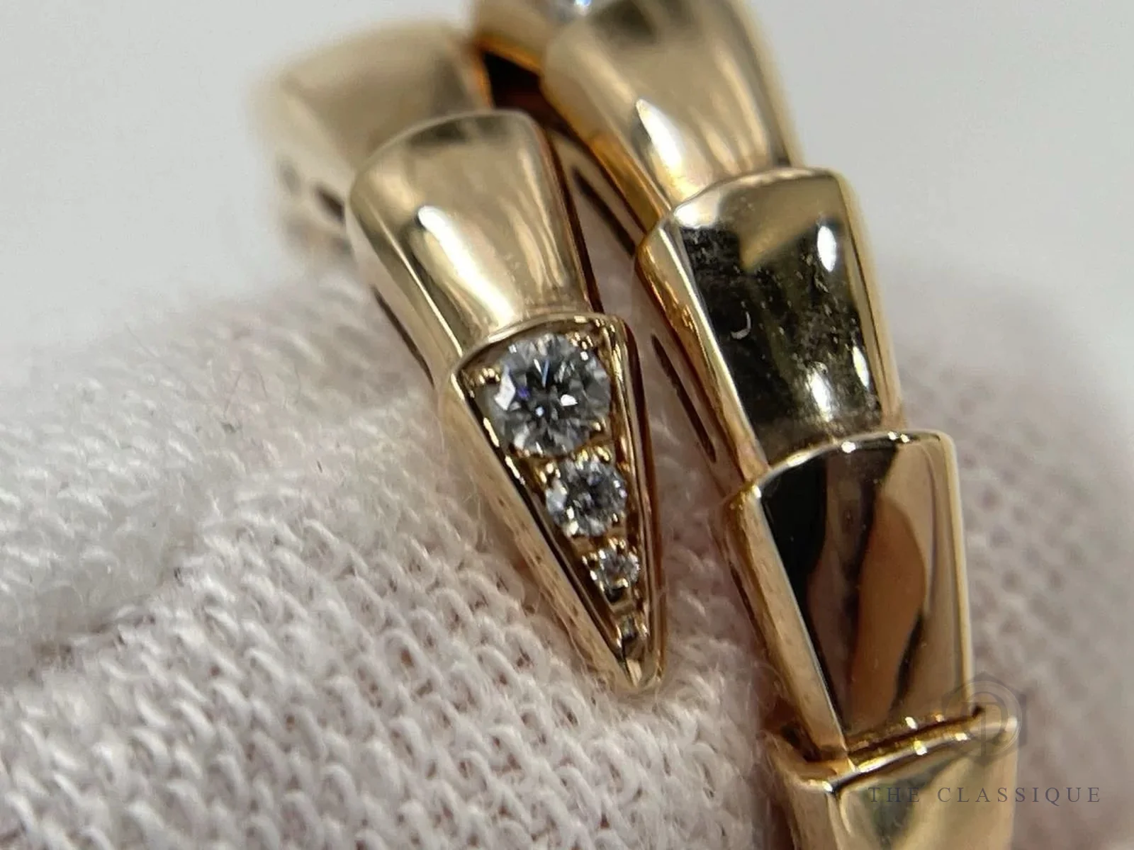 Đầu nhẫn Bvlgari Serpenti Viper vàng hồng đính ba viên kim cương nhỏ dần, đặt trên găng vải