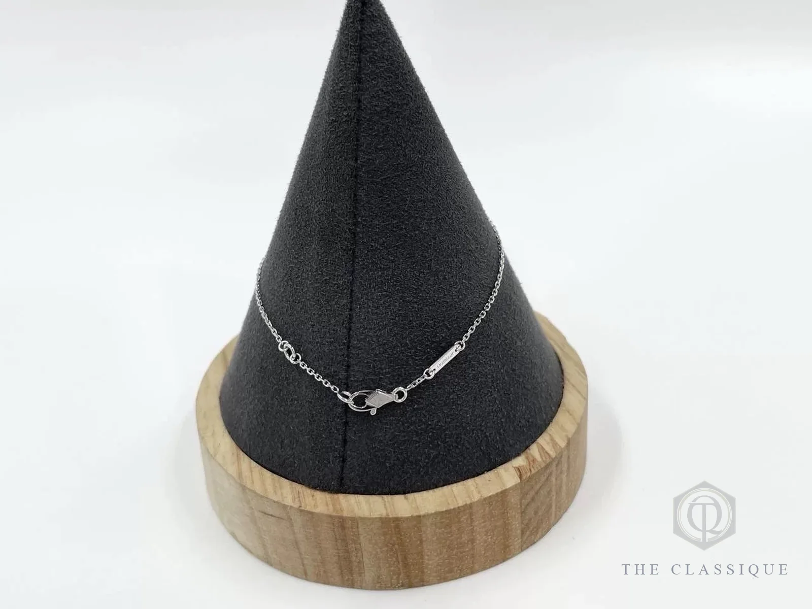 Khoá móc và thanh khắc dấu trên dây vòng tay Van Cleef Frivole vàng trắng, đặt trên nón trưng bày đen