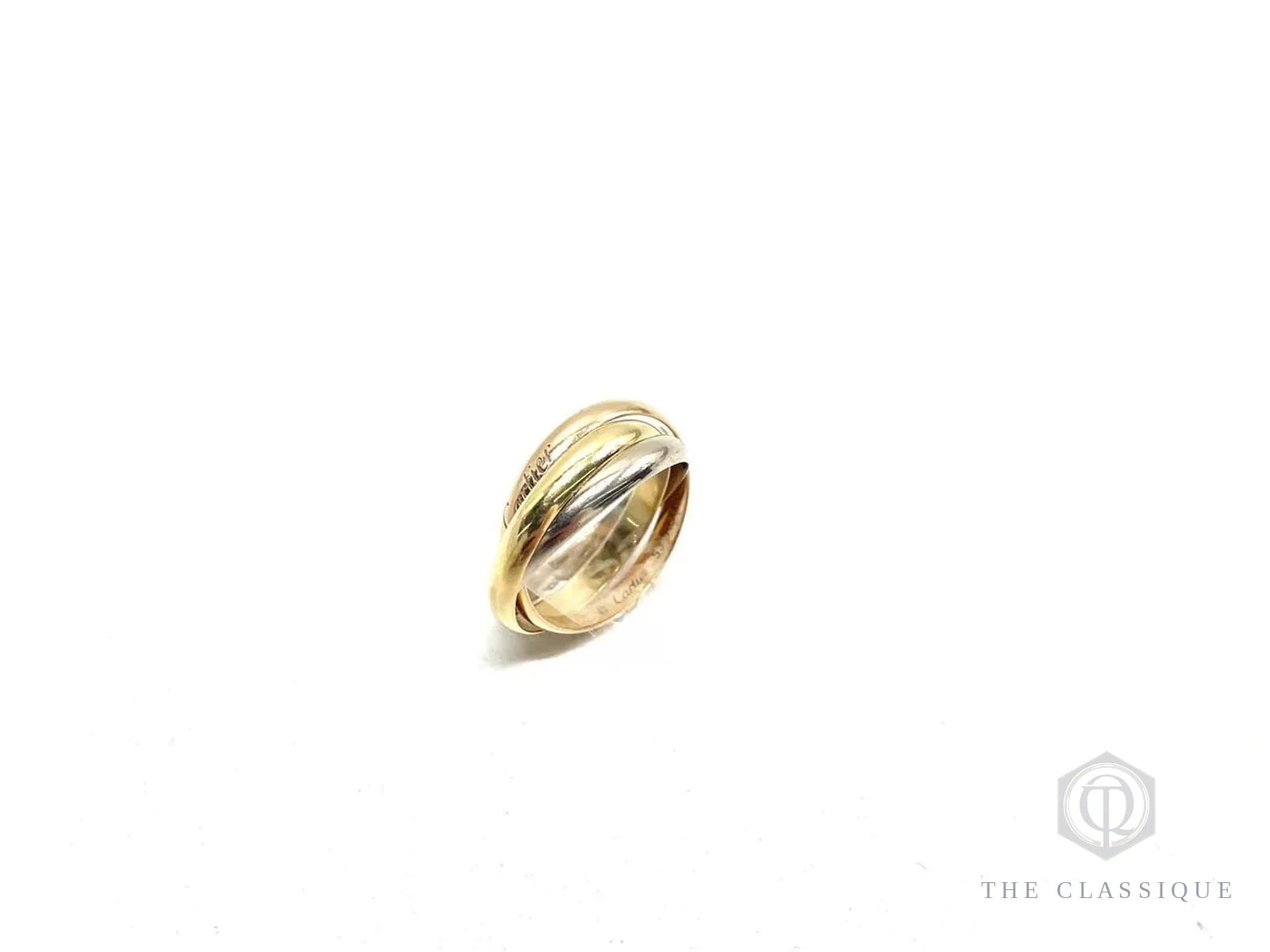 Ba vòng nhẫn Cartier Trinity ba màu vàng lồng vào nhau, chụp nghiêng trên nền trắng