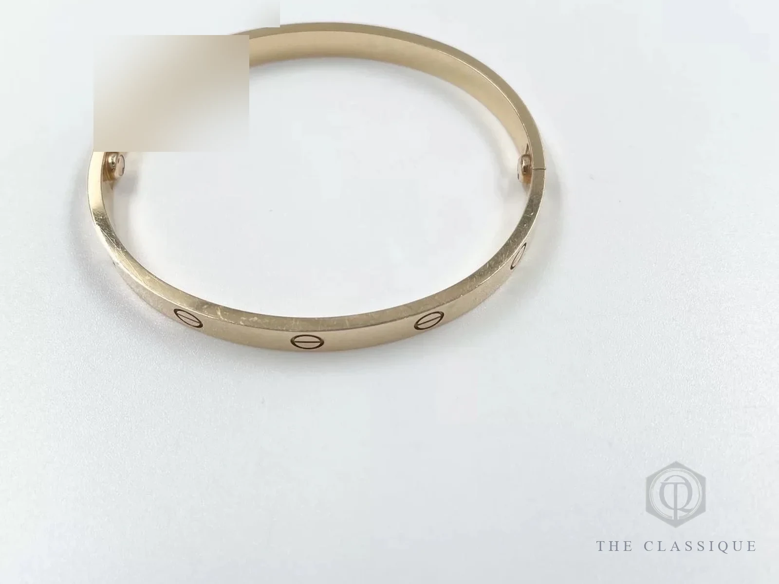 Vòng Cartier Love vàng hồng soi nghiêng, thấy các vết xước dăm nhỏ trên mặt vàng