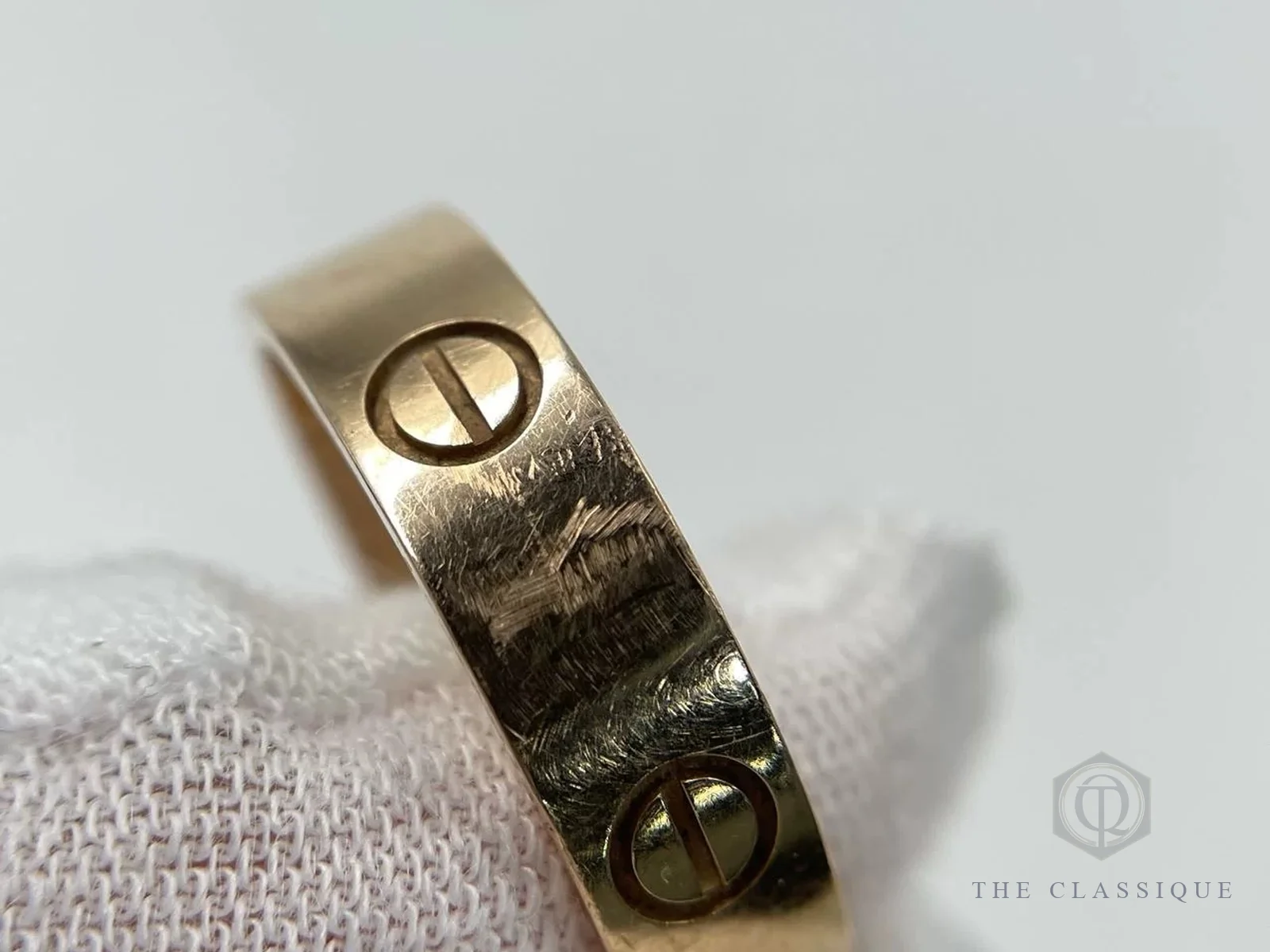 Mặt ngoài nhẫn Cartier Love vàng đã qua sử dụng với nhiều vết xước dăm quanh hoạ tiết ốc vít