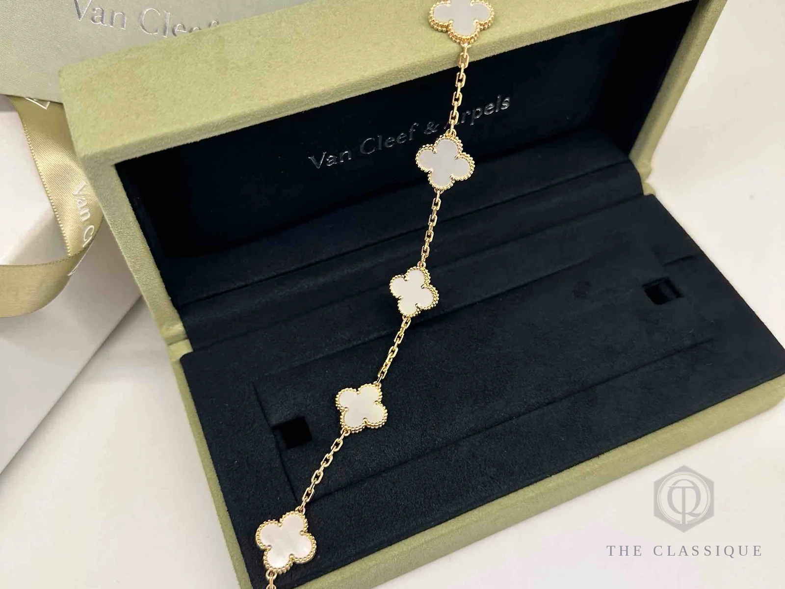 Vòng tay Van Cleef Alhambra mặt xà cừ nằm trong hộp và sổ bảo hành chính hãng, chuẩn bị mang đi bán