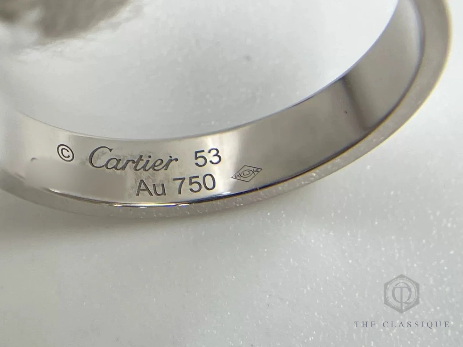 Chữ khắc Cartier, size 53 và Au 750 cùng dấu xưởng hình thoi trên mặt trong nhẫn Cartier Love vàng trắng