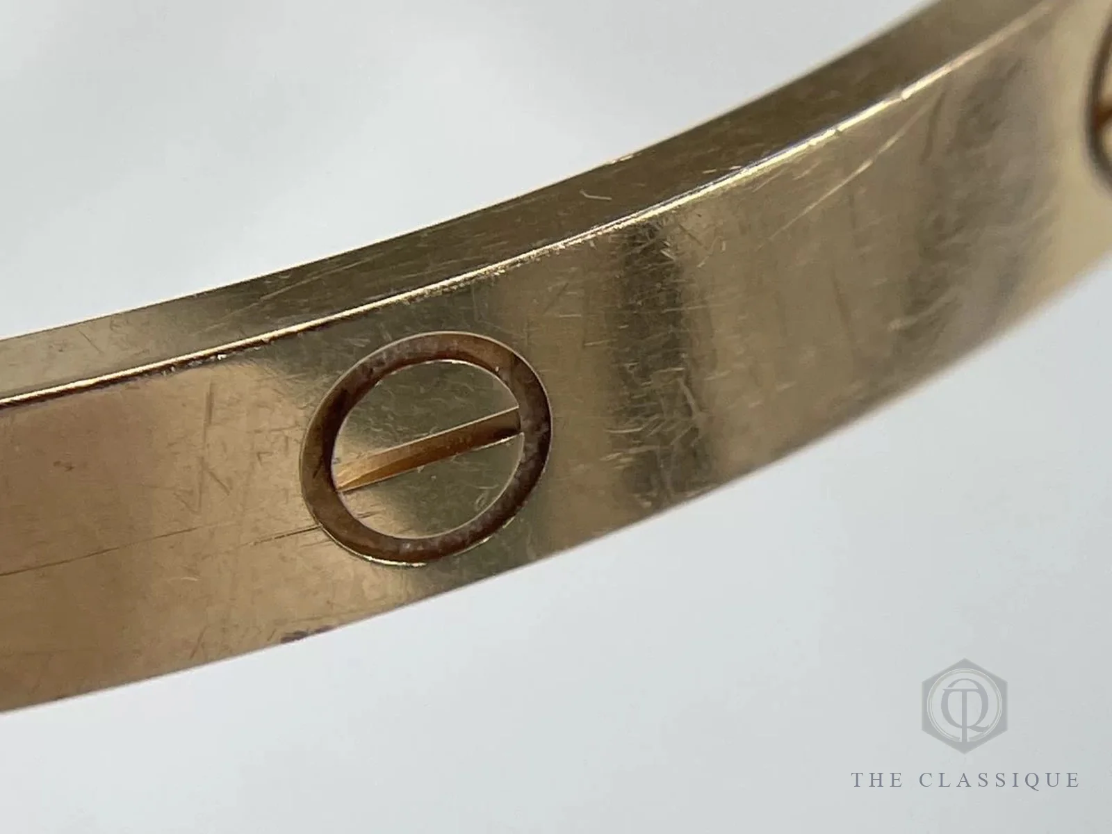 Cận cảnh bề mặt vòng Cartier Love vàng hồng với nhiều vết xước dăm quanh ô ốc trang trí
