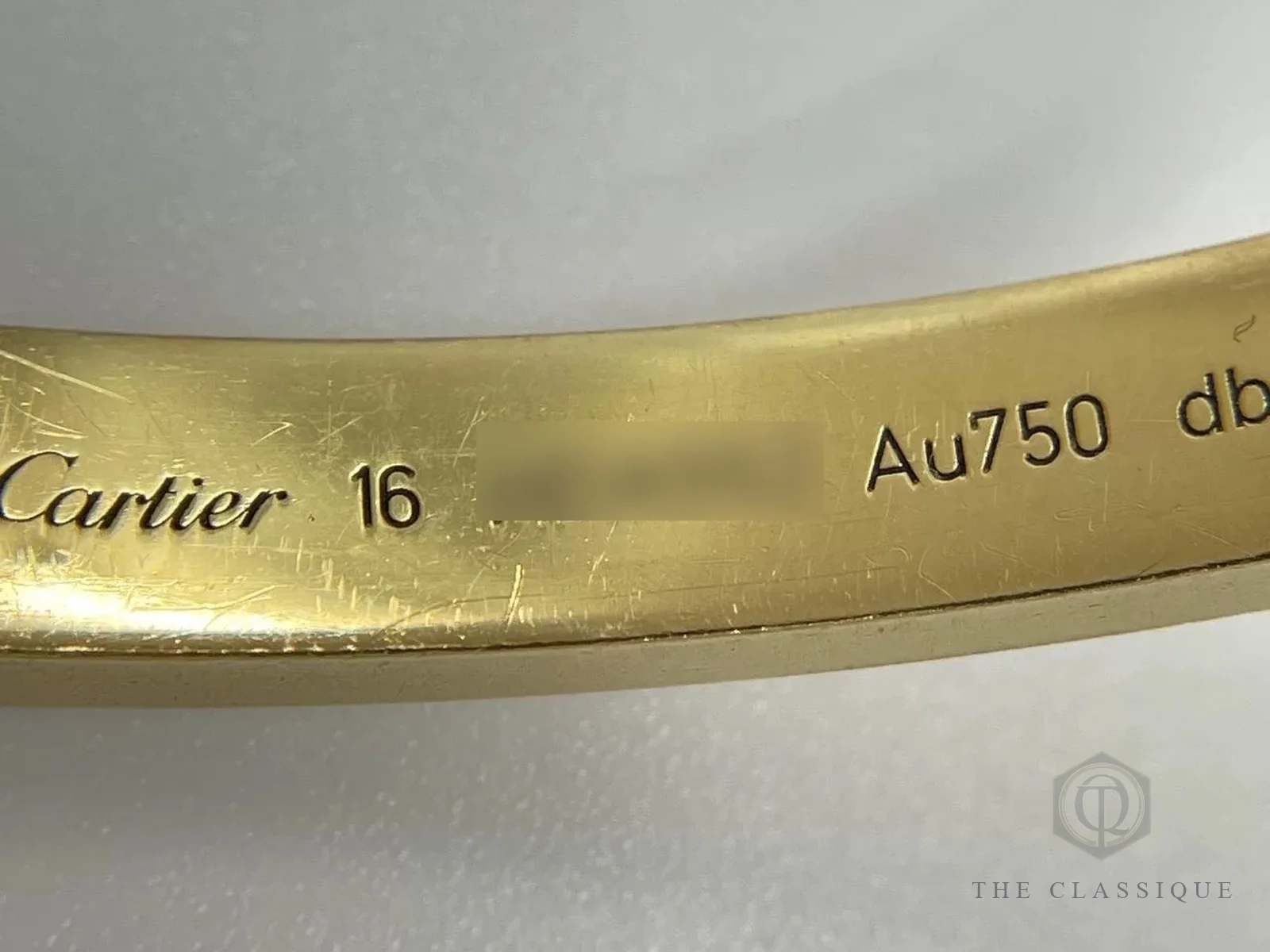 Chữ khắc gốc Cartier, số size 16 và ký hiệu Au750 ở mặt trong vòng Love, phần serial đã được che