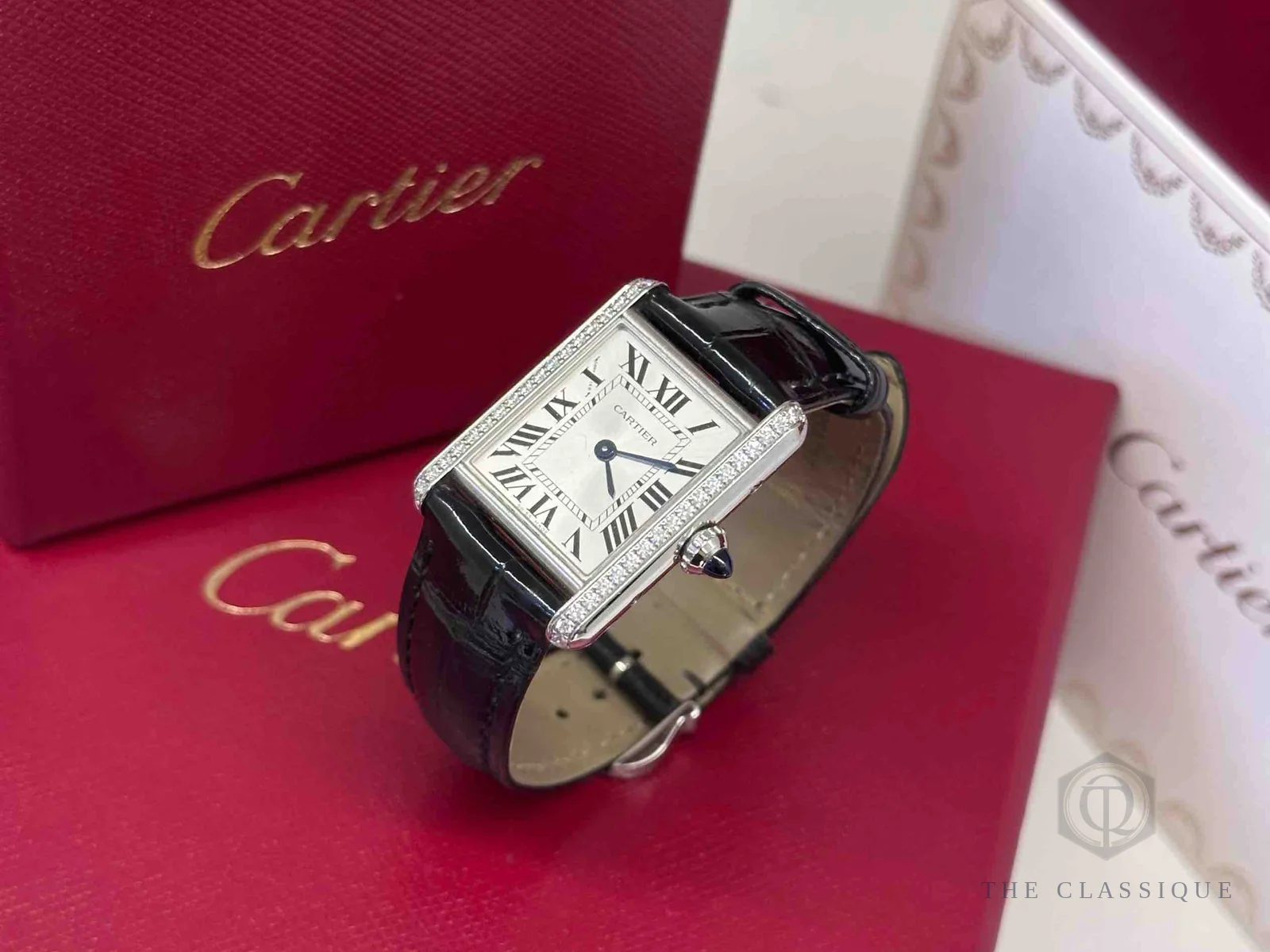 Đồng hồ Cartier thật giả, mặt số vuông số La Mã và viền đính kim cương chụp cận trên hộp đỏ chính hãng