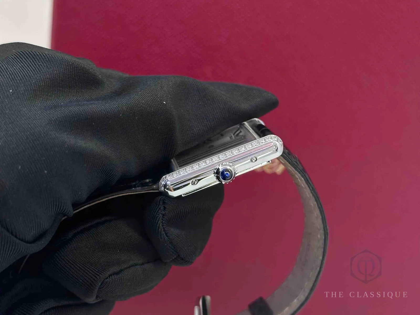 Cạnh vỏ đồng hồ Cartier với hàng kim cương đính viền và núm vặn đá cabochon xanh