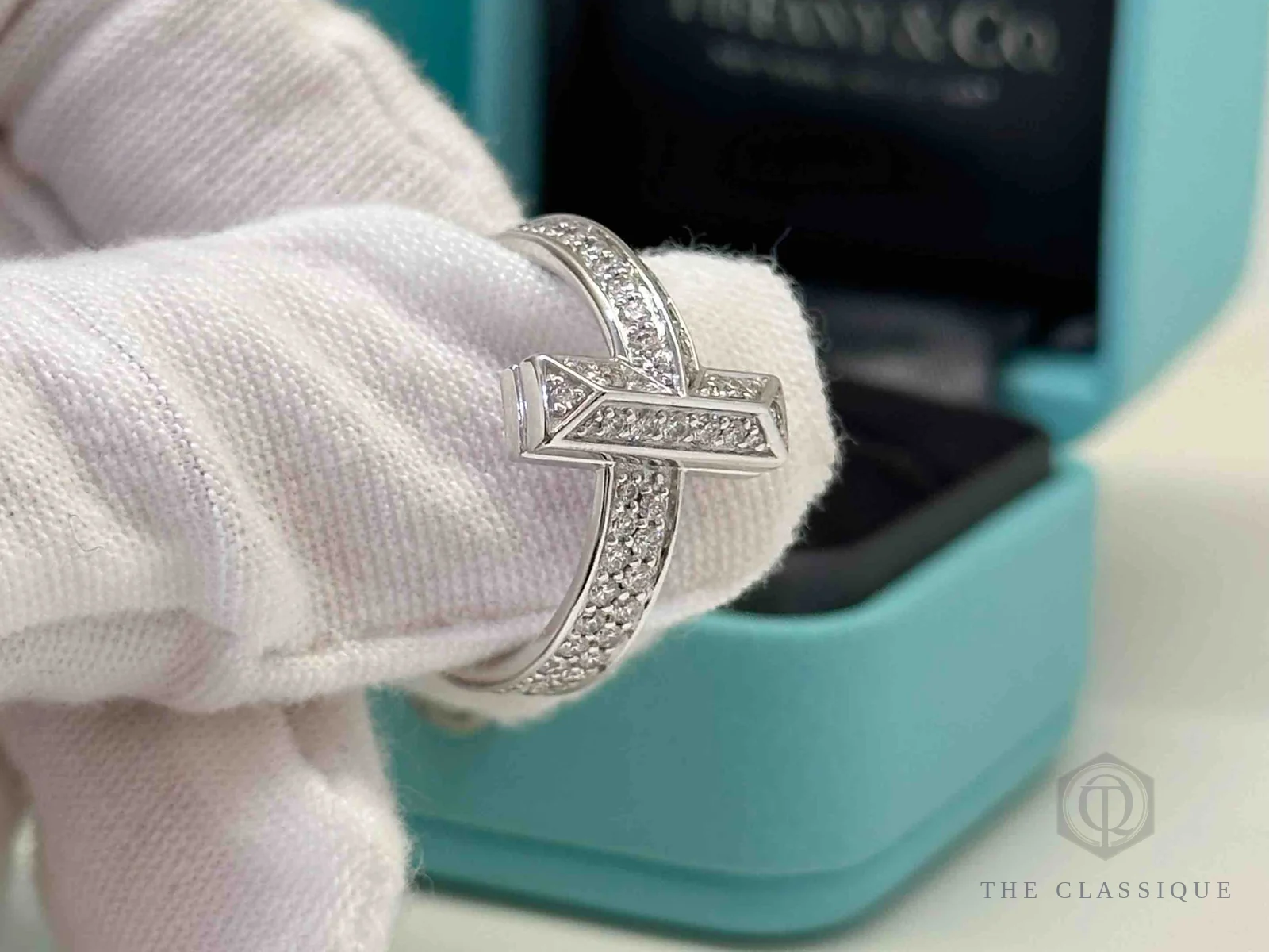 Nhẫn Tiffany T1 đính kim cương đeo trên tay, cạnh kim loại giữa các ô đá mài phẳng và đều