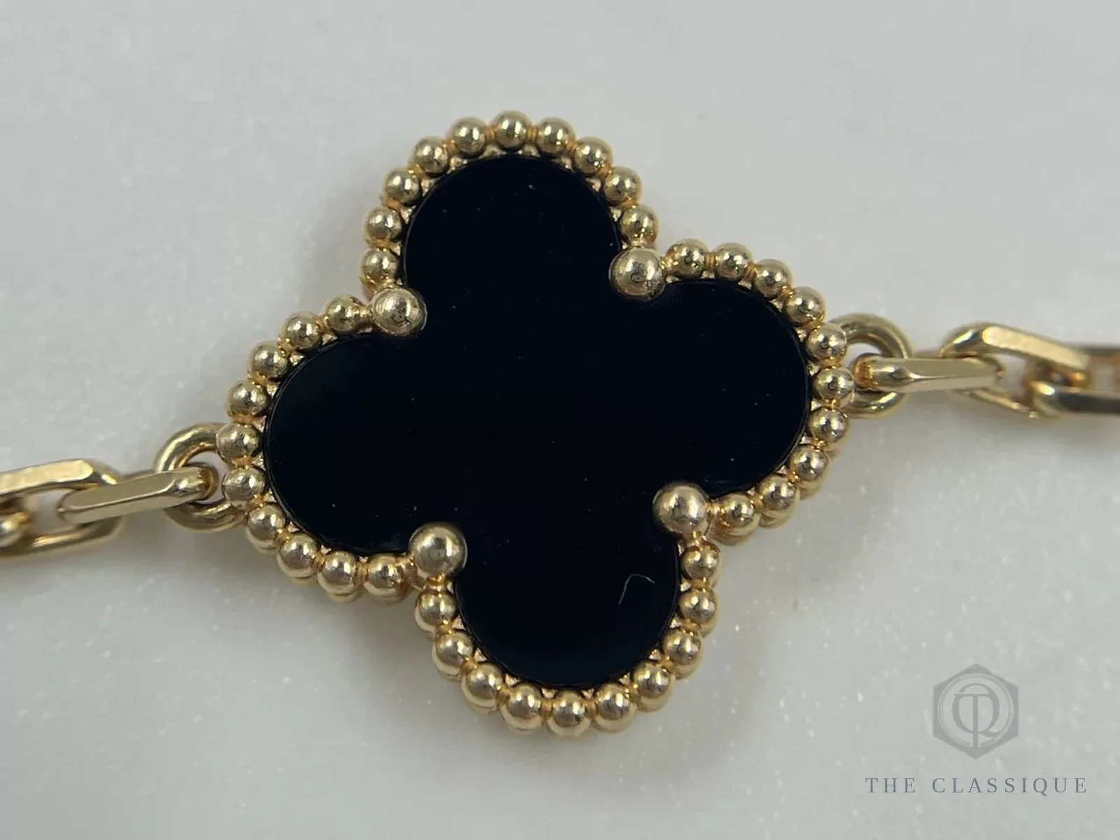Viền hạt vàng tròn đều quanh mặt đá onyx đen trên một motif Van Cleef Alhambra thật