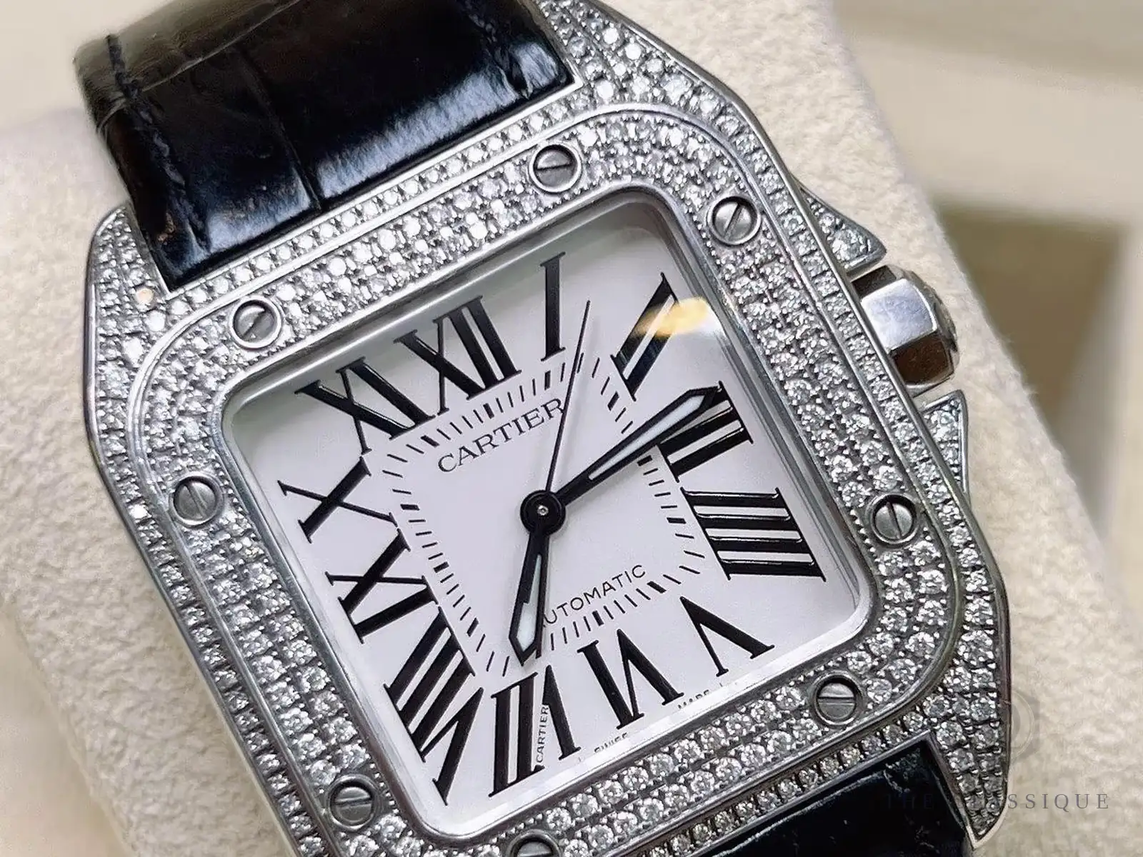 Ốc vít bezel nổi giữa lớp kim cương pave trên vỏ Cartier Santos