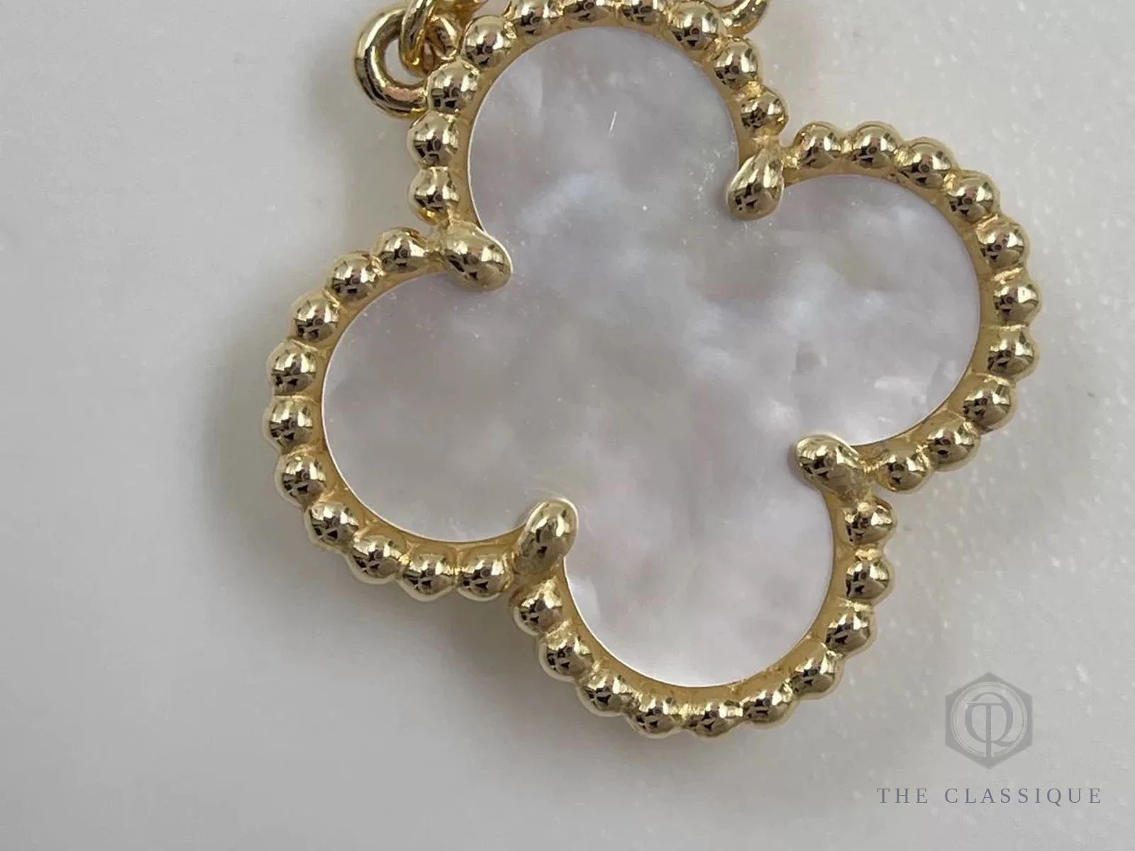 Mặt dây chuyền cỏ 4 lá Van Cleef Alhambra, motif xà cừ trắng viền hạt vàng nhìn cận cảnh