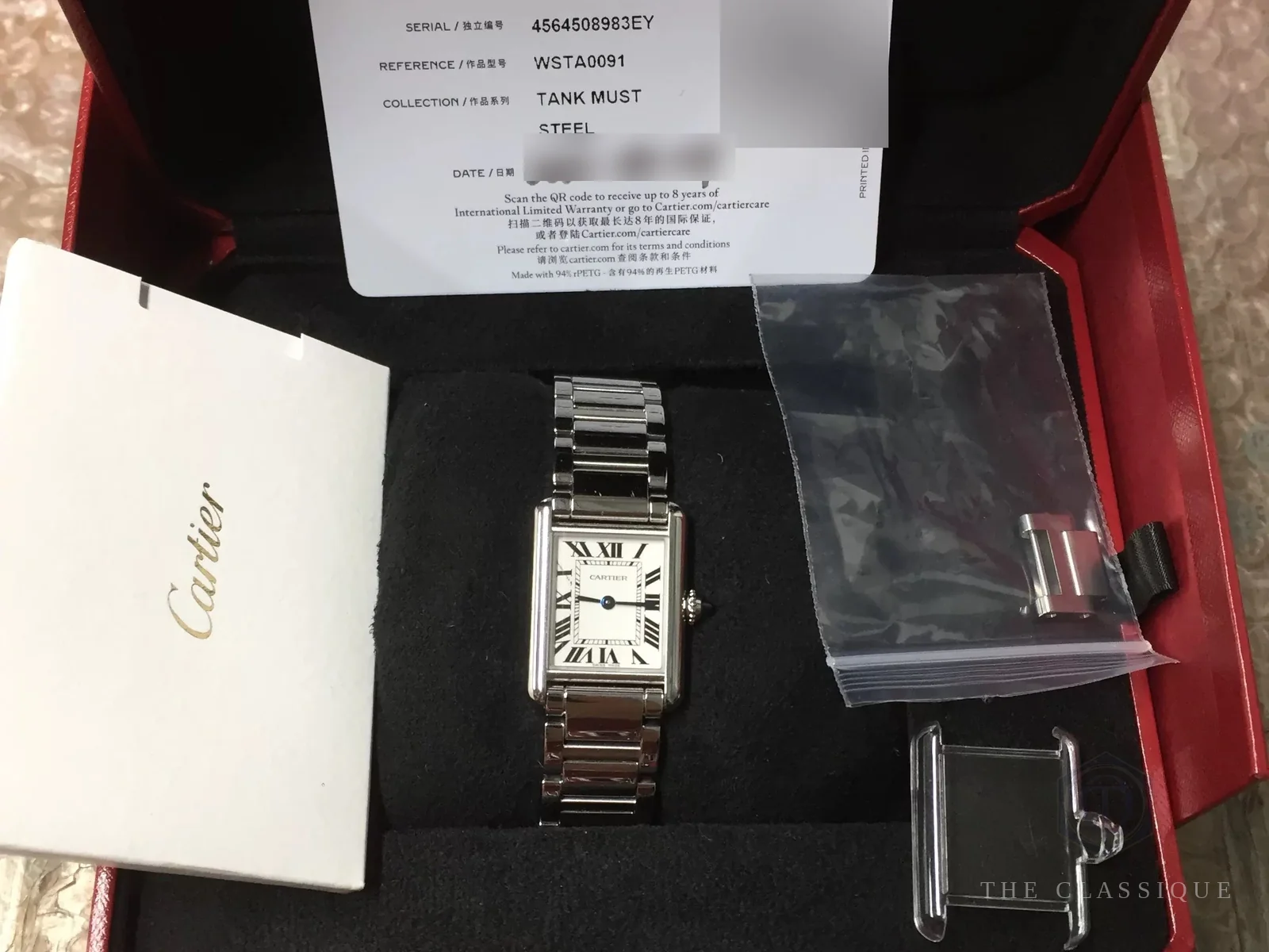 Đồng hồ Cartier Tank Must còn nguyên hộp đỏ Cartier, kèm thẻ bảo hành ghi collection Tank Must và dây kim loại tháo lắp nhanh