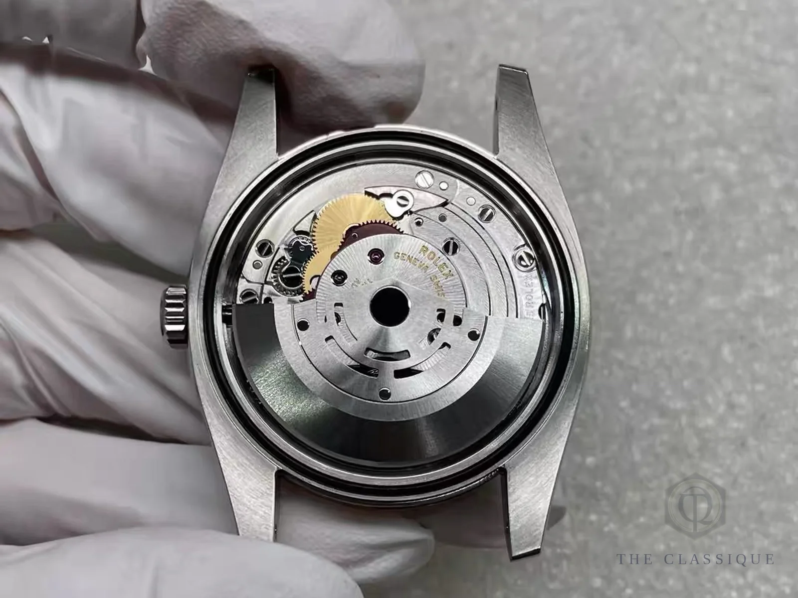 Nắp đáy mở lộ bộ máy automatic, rotor khắc chữ Rolex Geneva Swiss, người thợ cầm trên tay có đeo găng