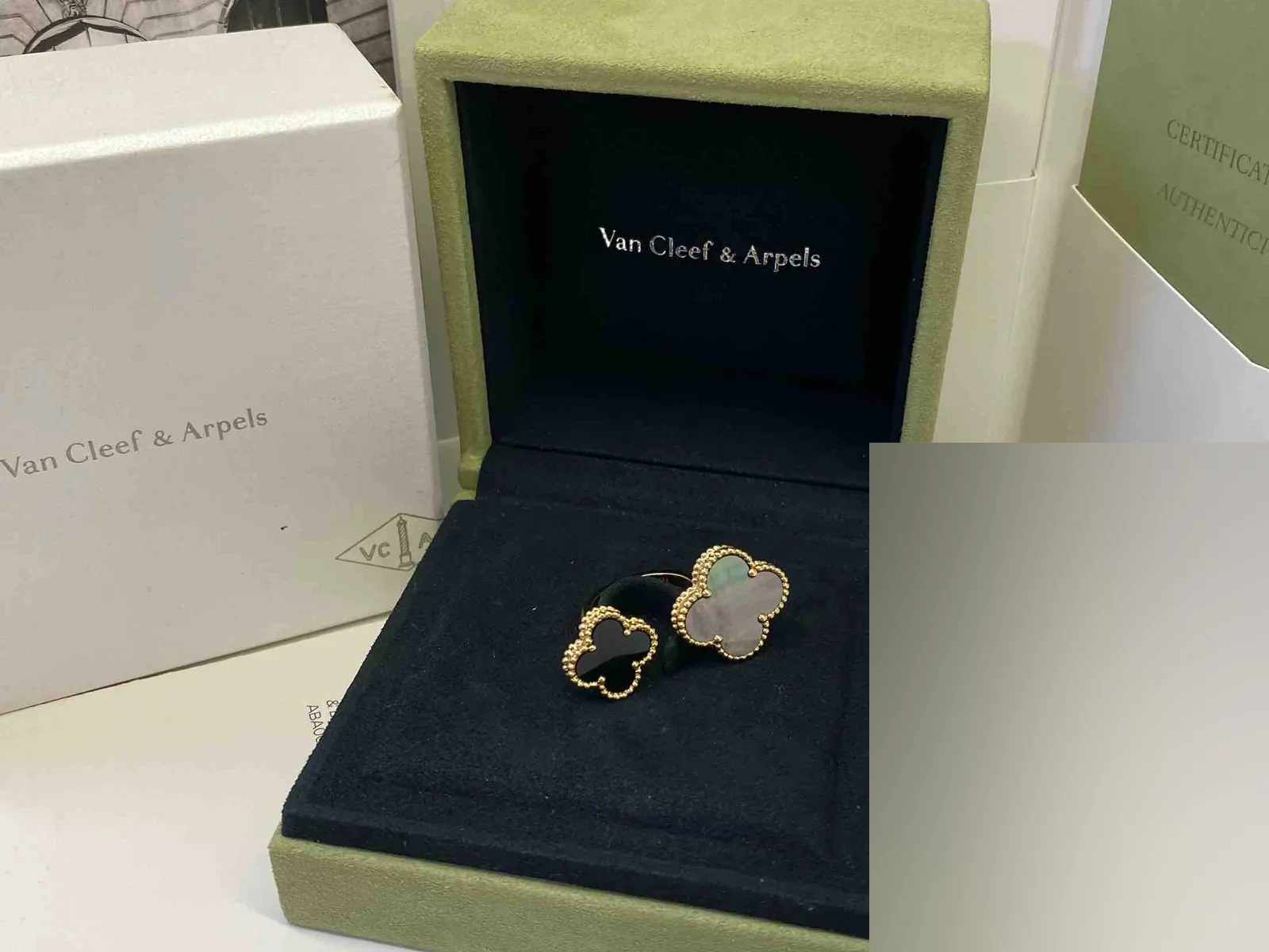 Hộp nhung xanh Van Cleef Arpels cùng giấy tờ đi kèm một chiếc nhẫn Alhambra hai mặt đá
