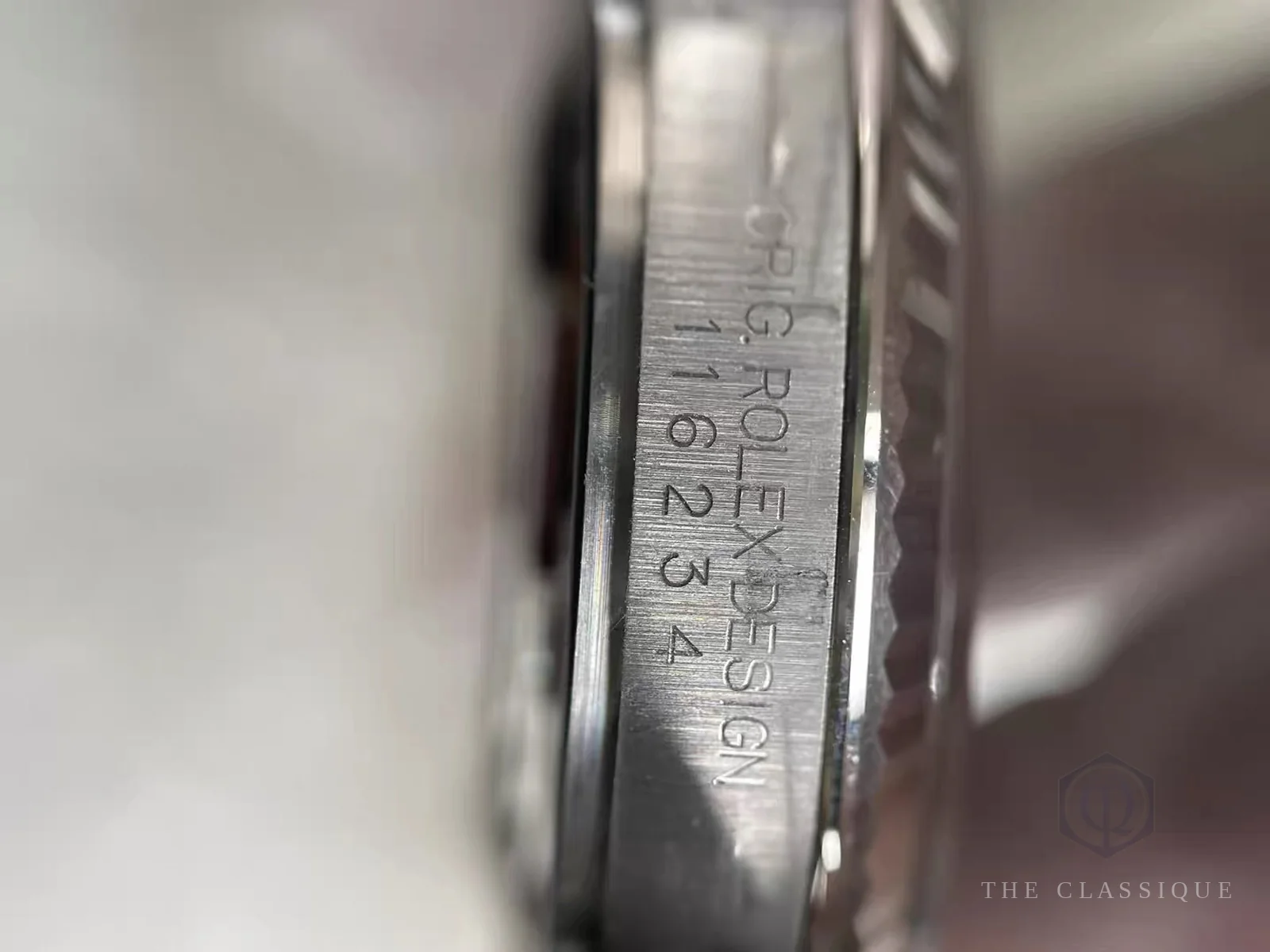 Dòng chữ ORIG. ROLEX DESIGN và mã tham chiếu khắc giữa hai tai đồng hồ Rolex, tháo dây mới nhìn thấy