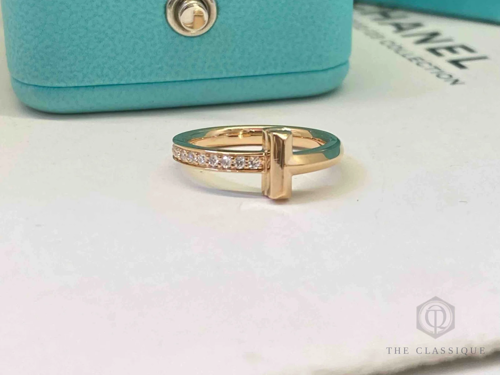 Nhẫn Tiffany T Wire rose gold đính kim cương đặt cạnh hộp Tiffany xanh
