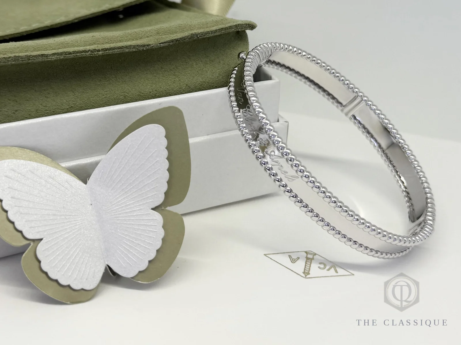 Van Cleef Perlée hạt vàng trắng size XS đặt cạnh hộp và cánh bướm trang trí tại The Classique