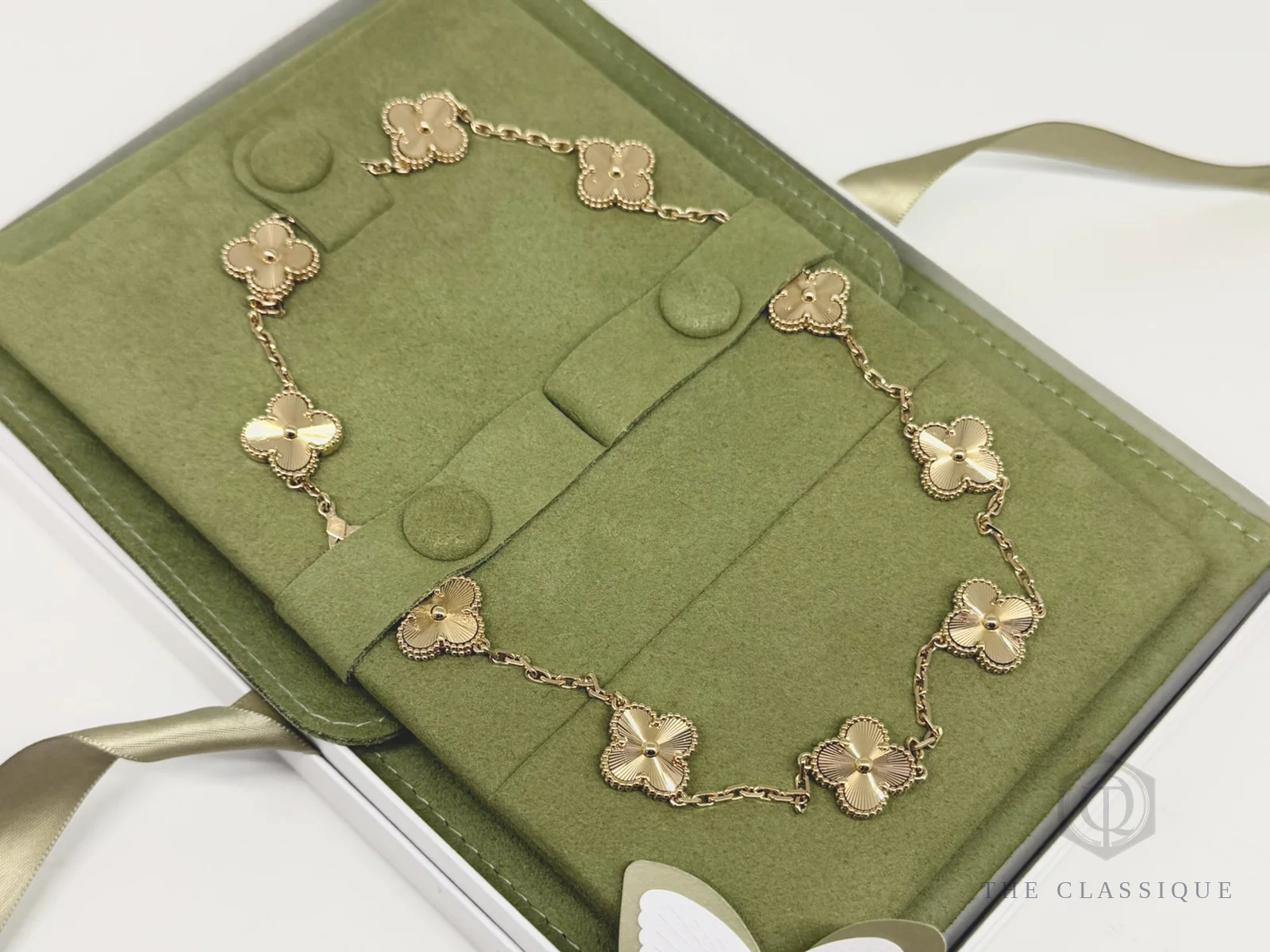 Dây chuyền Van Cleef Alhambra mười mắt hoa vàng vàng đặt trong hộp lót vải xanh rêu